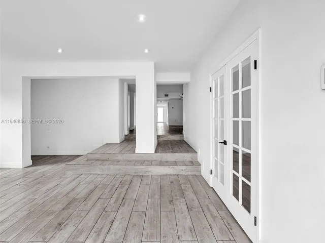 a view of a hallway with wooden floor and a bathroom
