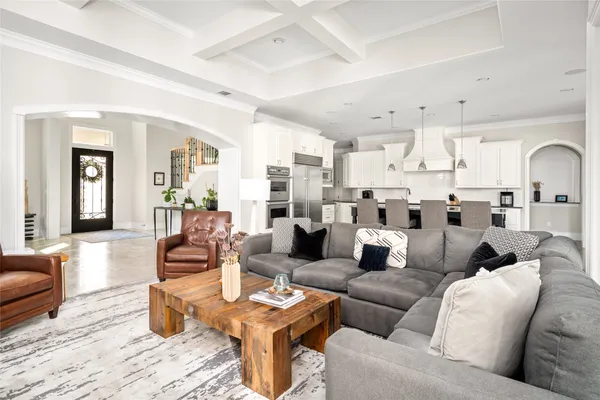a living room with furniture kitchen view and a wooden floor