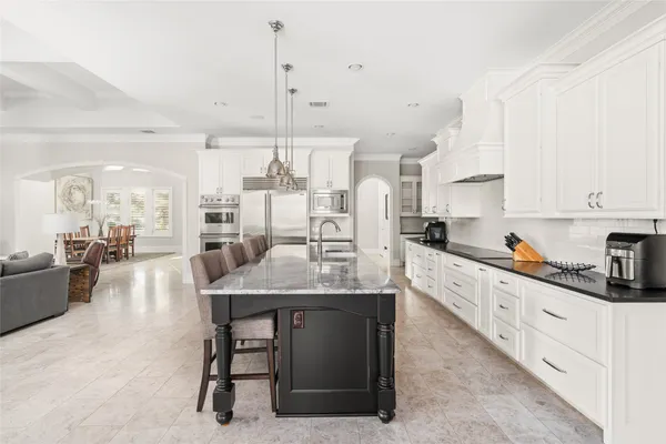 a large kitchen with granite countertop a stove top oven a sink dishwasher a dining table and chairs with wooden floor