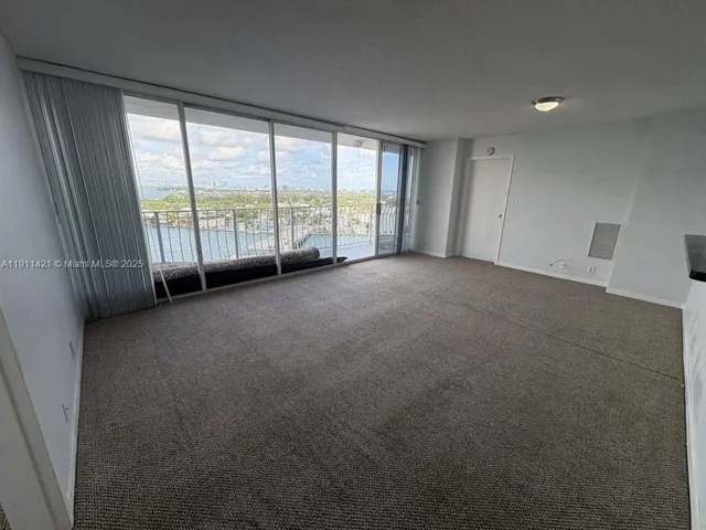 a view of an empty room with wooden floor and stairs