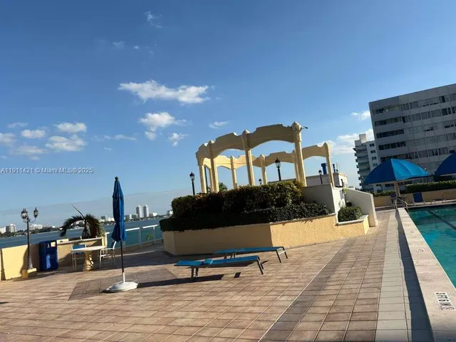 a swimming pool with barbeque oven table and chairs