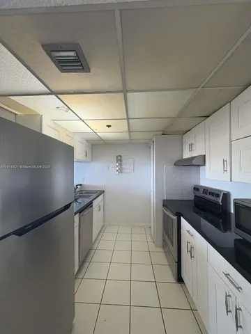 a kitchen with white cabinets a refrigerator and a sink