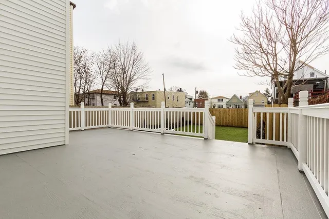 a view of a deck with large trees and wooden fence