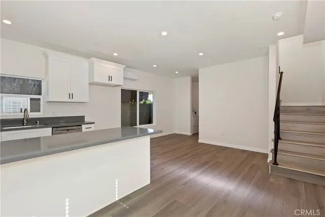 a large kitchen with stainless steel appliances a large counter top a wooden floor and a sink