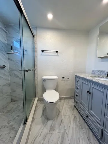 a bathroom with a granite countertop toilet a sink and a shower
