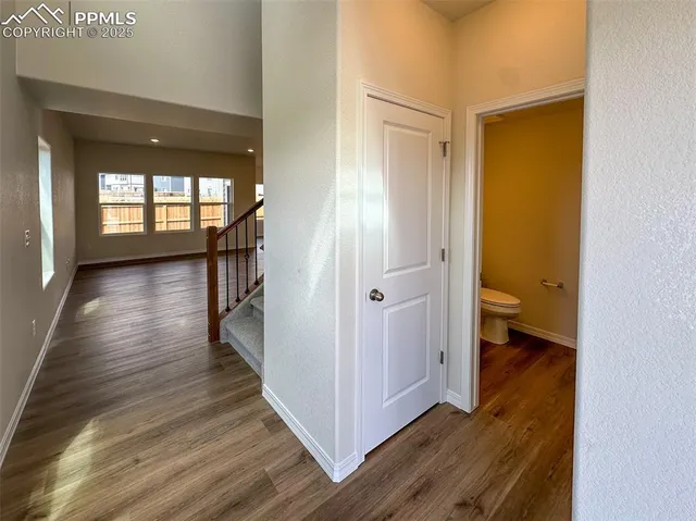 a view of a hallway with wooden floor and a bathroom