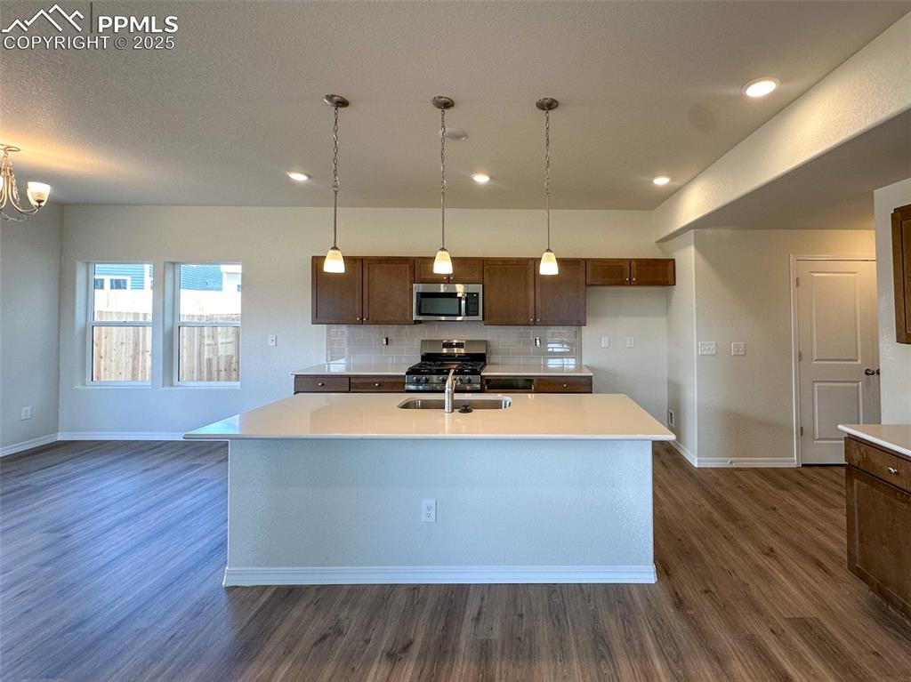 10820 Raylan Way Peyton, CO 80831 - Photo 5 of 35 a large kitchen with kitchen island a stove a sink a refrigerator and a living room view
