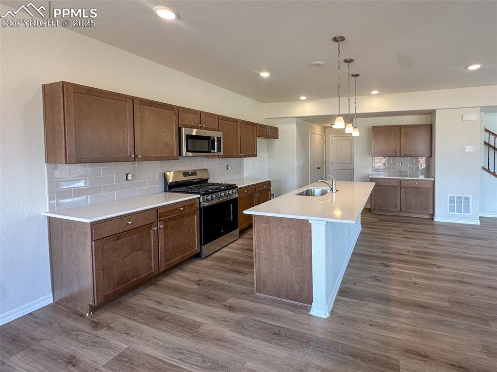 10820 Raylan Way Peyton, CO 80831 - Photo 10 of 35 a large kitchen with stainless steel appliances kitchen island a large counter top a sink a stove and a refrigerator