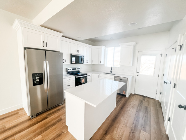 522 West 2000 South Vernal, UT 84078 - Photo 13 of 18 Kitchen with stainless steel appliances, white cabinets, dark wood-style floors, a center island, and light stone countertops