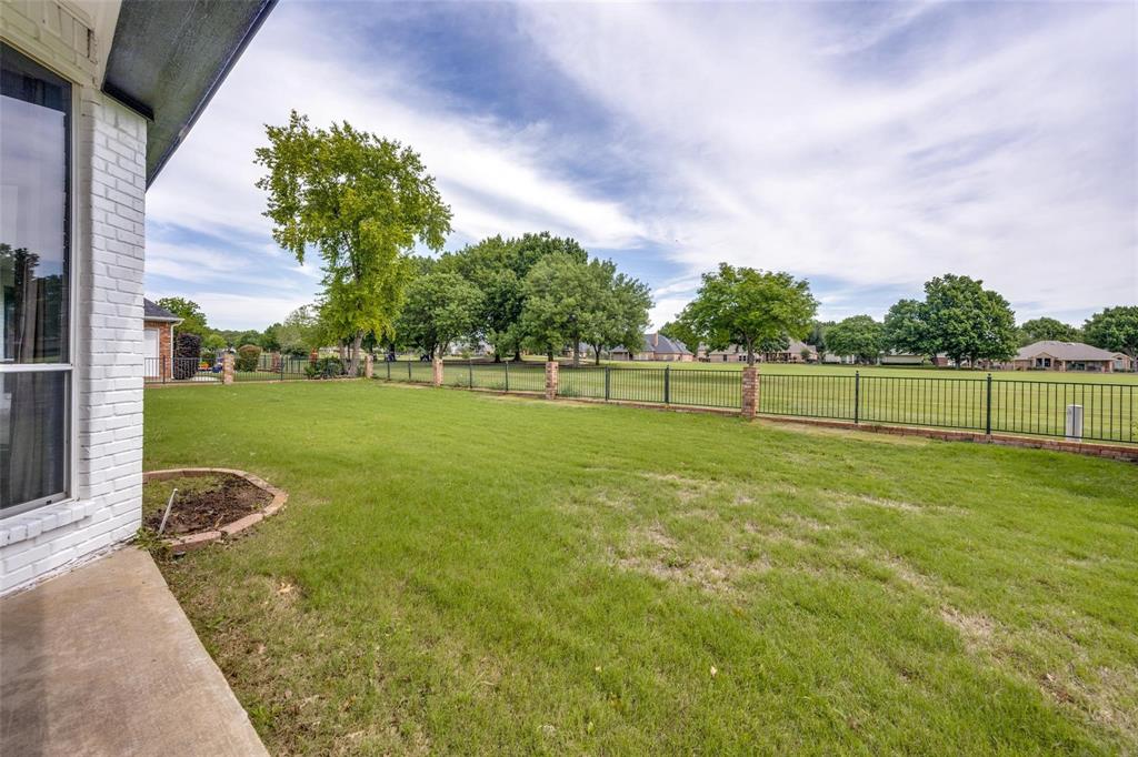 818 Riviera Drive Mansfield, TX 76063 - Photo 3 of 24 Expansive backyard with a large lawn, framed by a black metal fence with stone pillars