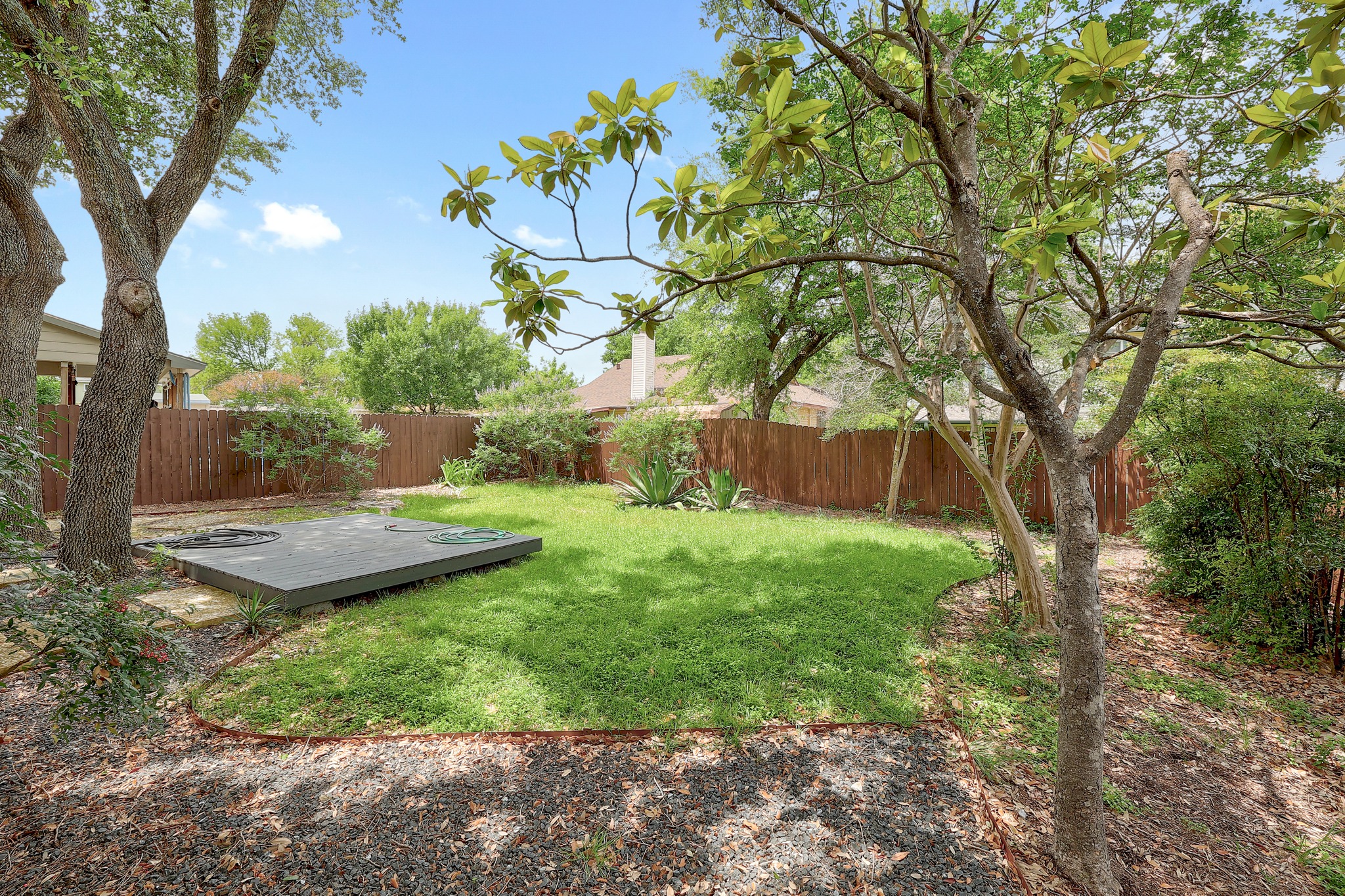 2202 Warfield Way Austin, TX 78728 - Photo 32 of 32 A verdant backyard offers a private oasis with mature trees and a wooden deck.