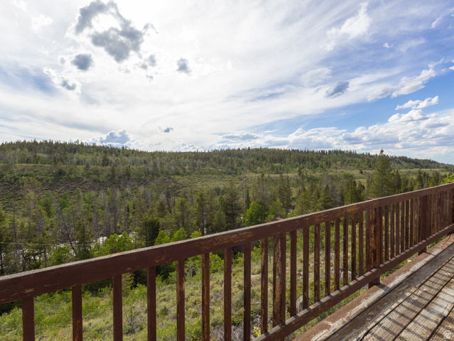 4770 Pine Crest Road Evanston, UT 82930 - Photo 7 of 24 Rustic wood-finish deck with slatted railing overlooking a forested landscape