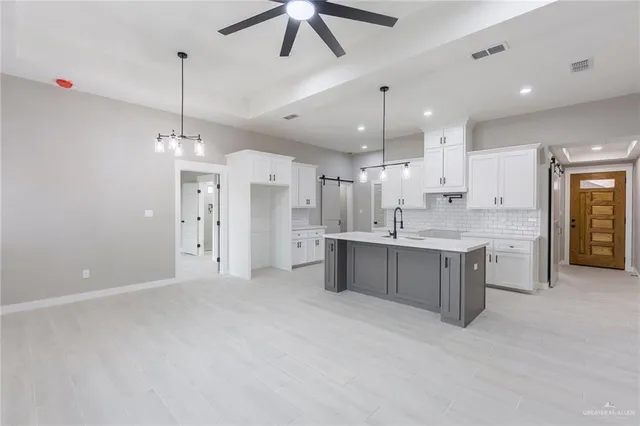 a large kitchen with a large counter top a sink stainless steel appliances and cabinets