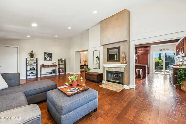 a kitchen with stainless steel appliances granite countertop a refrigerator a sink dishwasher a stove and a dining table with wooden floor