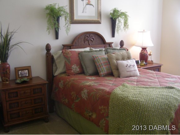 4623 Rivers Edge Village Lane, Unit 6208 Ponce Inlet, FL 32127 - Photo 11 of 23 a bedroom with a bed and with potted plants