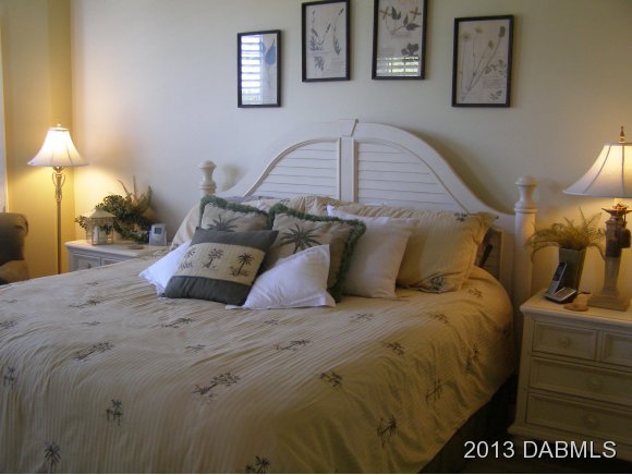 4623 Rivers Edge Village Lane, Unit 6208 Ponce Inlet, FL 32127 - Photo 6 of 23 a bedroom with a bed and a lamp