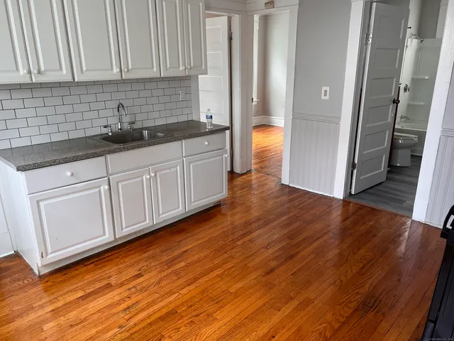 a kitchen with stainless steel appliances granite countertop a sink and cabinets with wooden floor