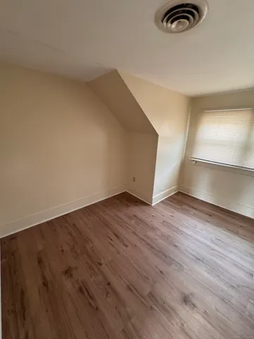 an empty room with wooden floor closet and windows