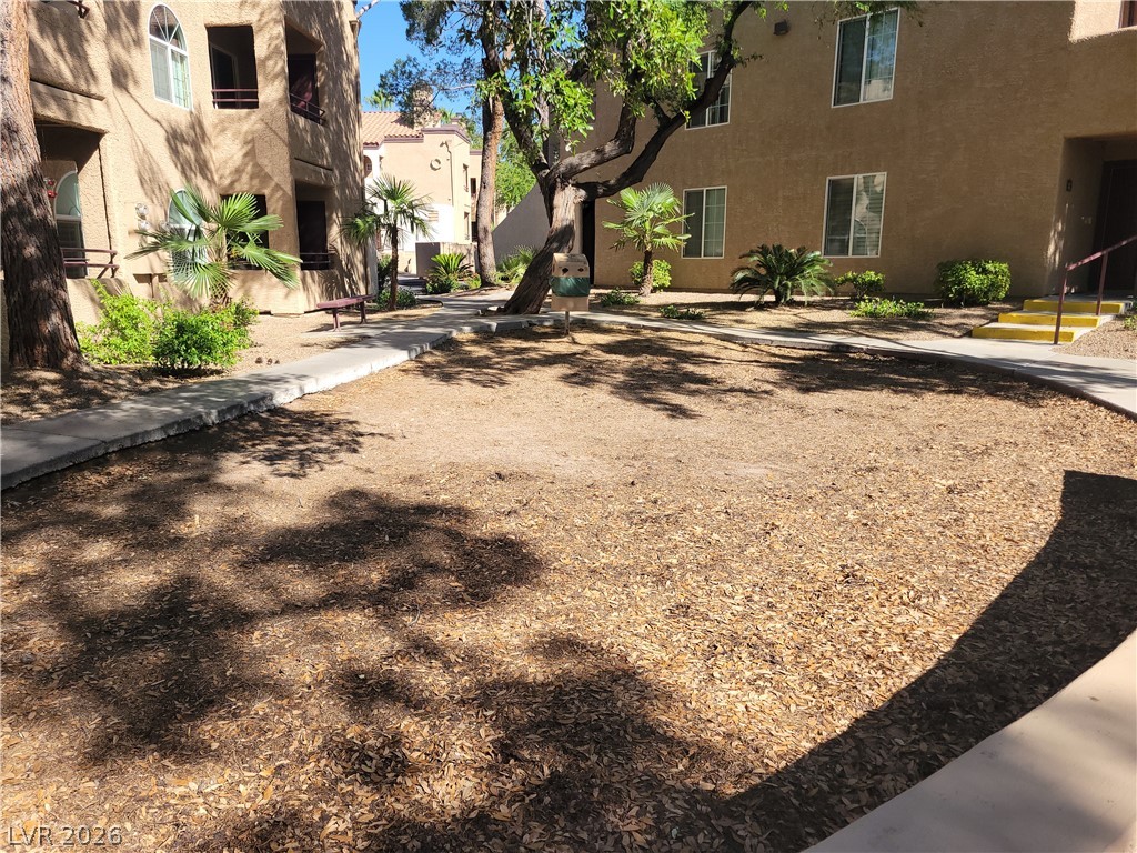 9325 West Desert Inn Road, Unit 178 Las Vegas, NV 89117 - Photo 20 of 20 Mature trees shade a communal courtyard flanked by multi-story stucco buildings.