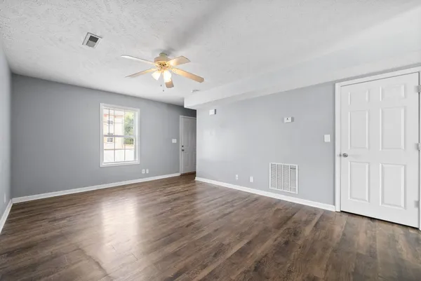 a view of an empty room with a window and wooden floor