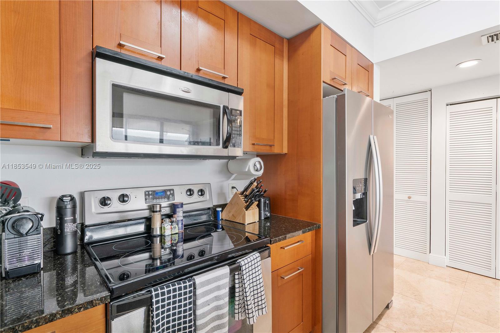 4100 Salzedo Street, Unit 409 Coral Gables, FL 33146 - Photo 14 of 45 a kitchen with stainless steel appliances granite countertop a stove a microwave and a refrigerator