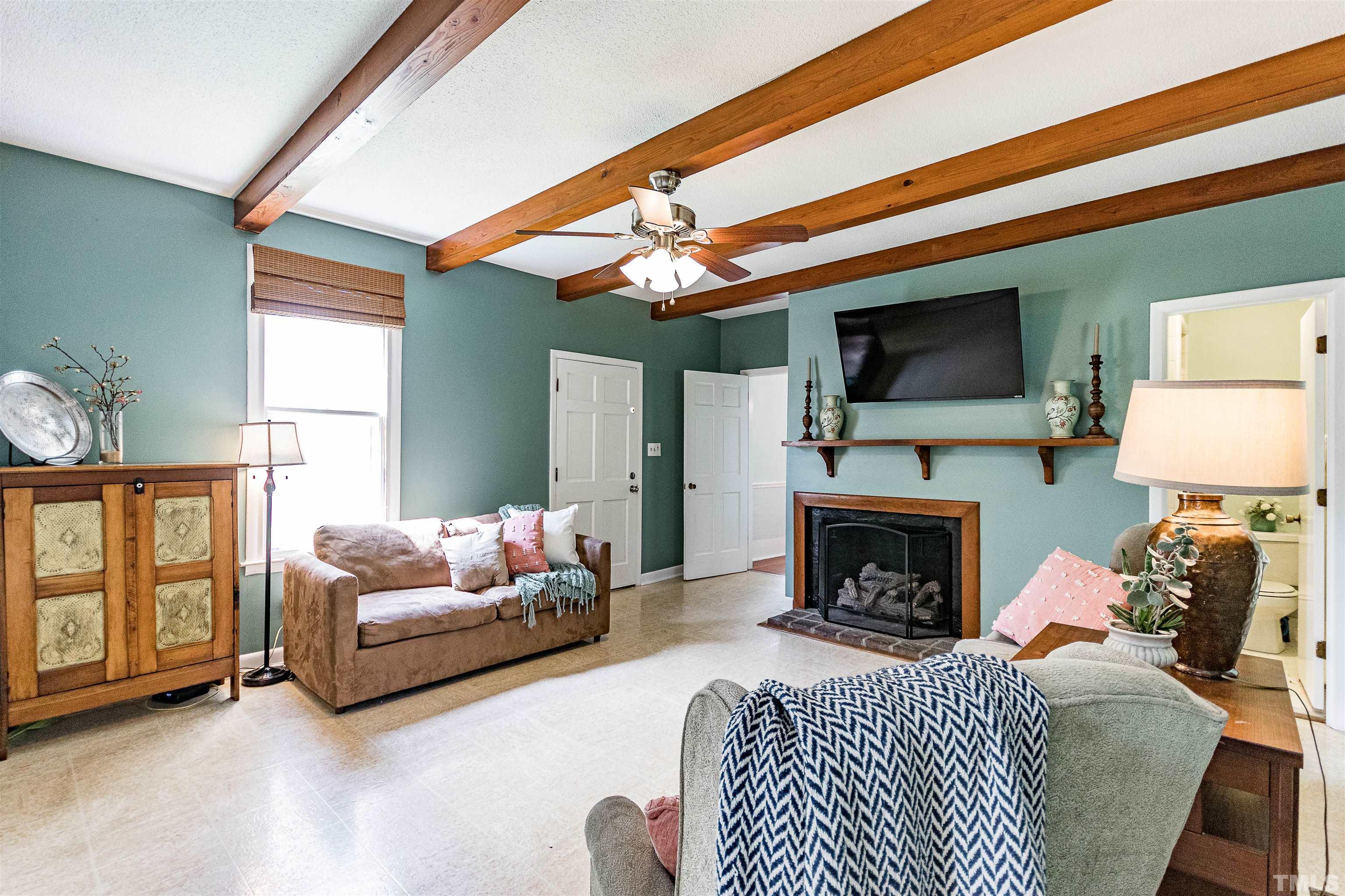6467 Cleveland Road Clayton, NC 27520 - Photo 16 of 54 Through the dining room you enter into the den, this cozy room with exposed wood beams, a wood burning fireplace, access to a full bathroom, laundry and flows into eat in kitchen.