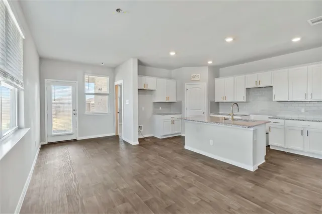 a kitchen with wooden floors white cabinets and appliances