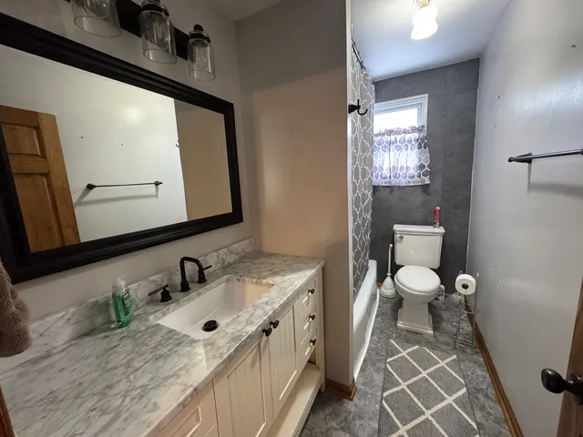 a bathroom with a granite countertop sink a mirror and a toilet