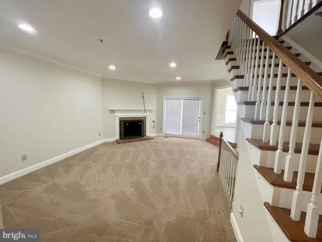 a view of an empty room with wooden floor and a fireplace