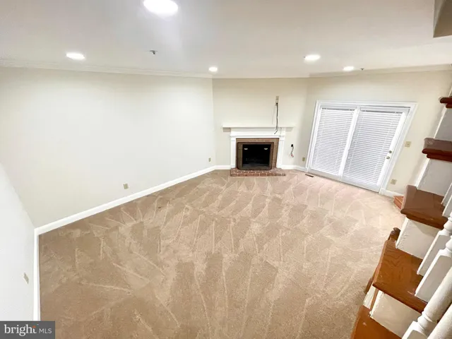 a view of empty room with fireplace and wooden floor