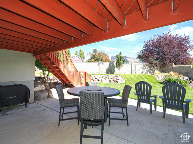 11779 South Stone Ridge Court Ridge West Riverton, UT 84065 - Photo 78 of 85 Covered concrete patio with direct access to a terraced backyard, featuring a manicured lawn, established landscaping, and a wooden exterior staircase