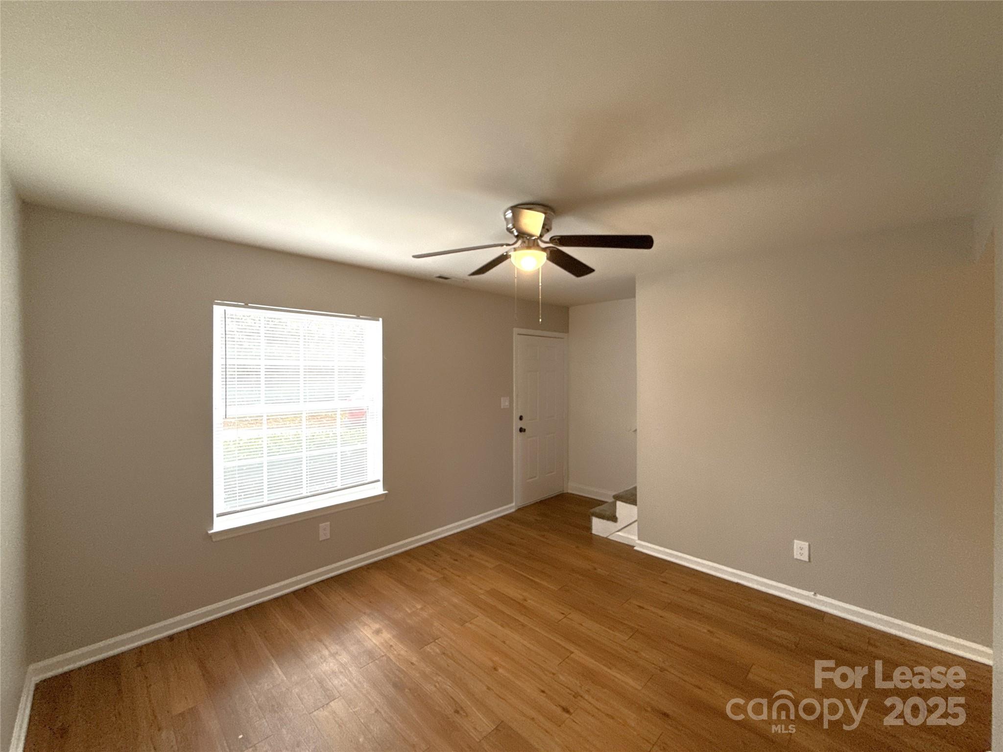 409 Hawley Avenue, Unit 7 Belmont, NC 28012 - Photo 3 of 12 an empty room with wooden floor chandelier fan and windows