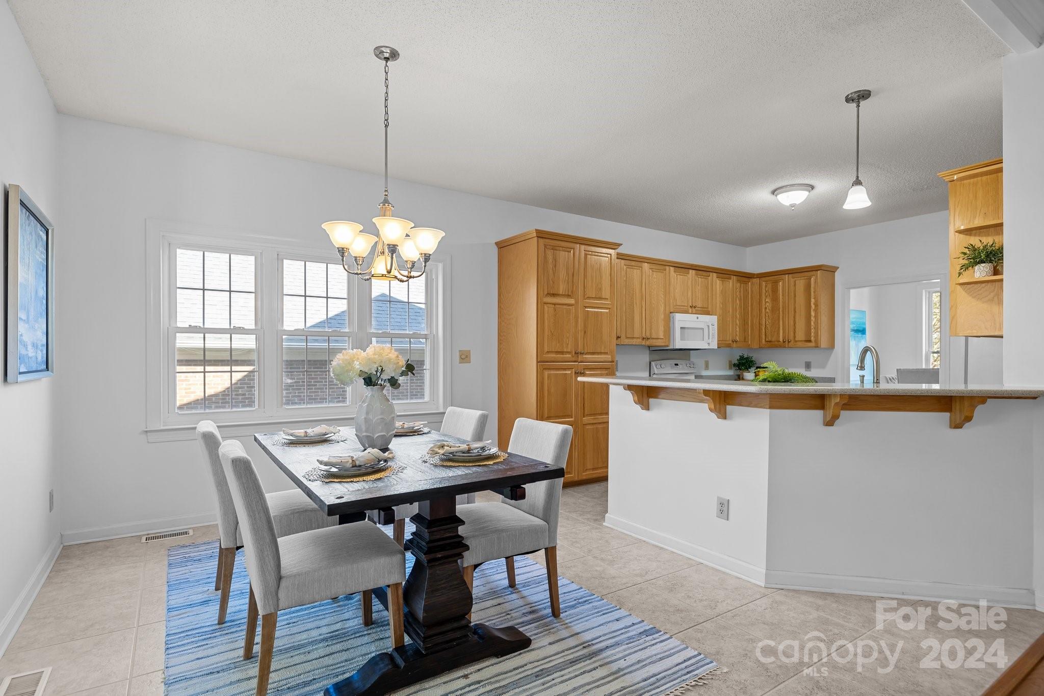 10508 Misty Ridge Lane Charlotte, NC 28277 - Photo 8 of 32 a kitchen with kitchen island dining table and a chandelier
