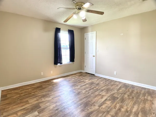 a view of an empty room with window and wooden floor
