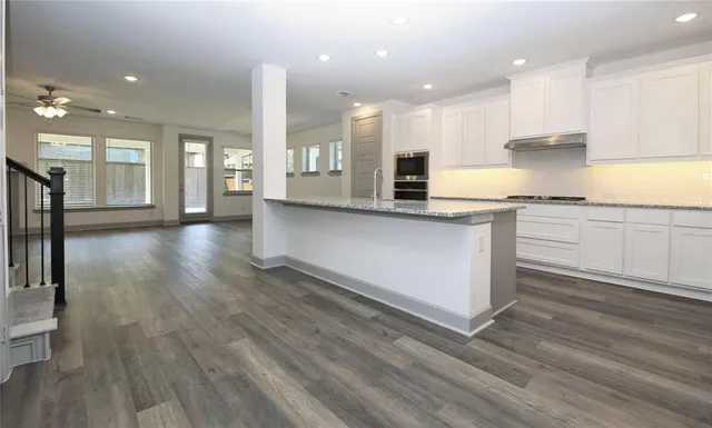 a large kitchen with stainless steel appliances granite countertop a lot of counter space and wooden floor
