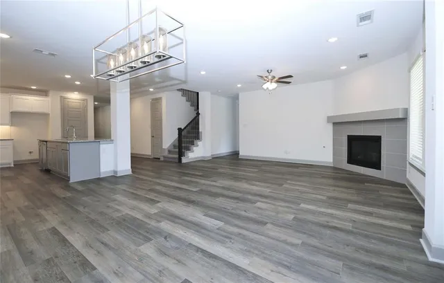 an empty room with wooden floor and a kitchen view