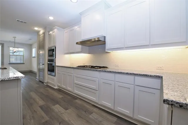 a kitchen with granite countertop white cabinets and stainless steel appliances