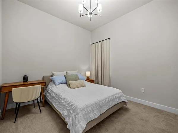 a bedroom with a bed a chair and a potted plant
