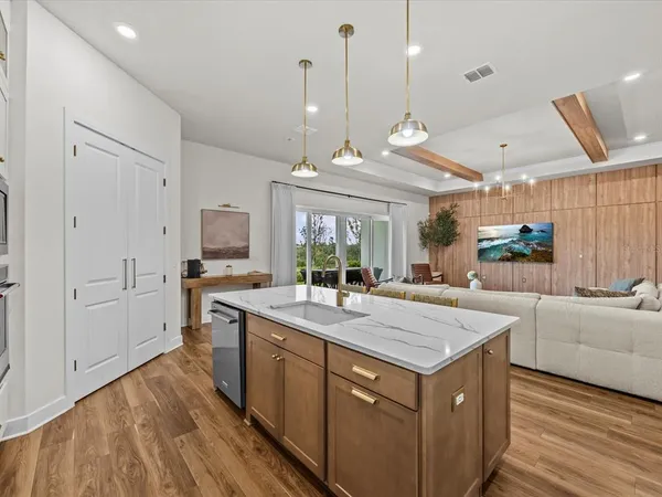 a large kitchen with kitchen island a stove a sink dishwasher and a fireplace with wooden floor