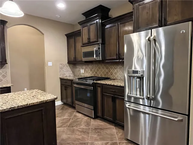 a kitchen with stainless steel appliances granite countertop a stove microwave and refrigerator