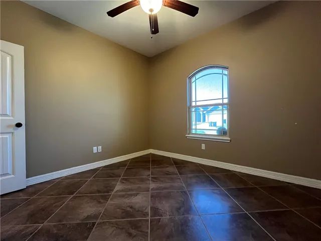 an empty room with wooden floor chandelier and windows