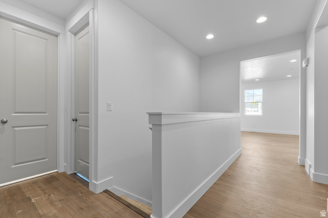 5644 Ibis Road Tooele, UT 84074 - Photo 7 of 19 Upper-level hallway featuring wood-finish flooring, recessed lighting, crisp white walls, and a contemporary half-wall railing