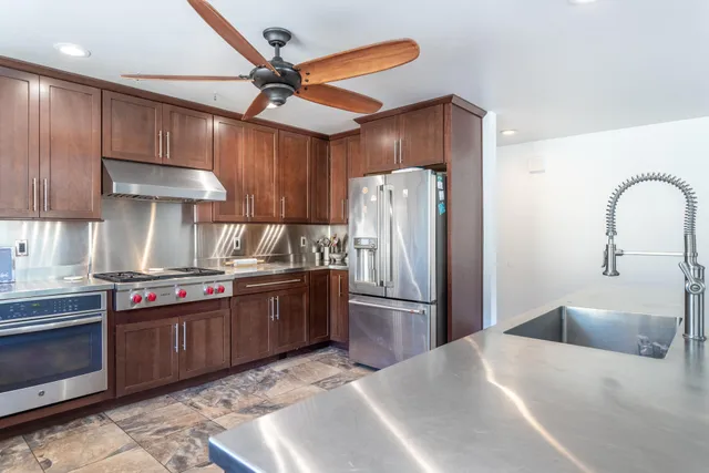 a kitchen with stainless steel appliances granite countertop a refrigerator and a stove top oven
