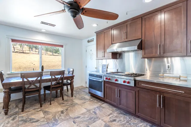 a kitchen with stainless steel appliances granite countertop wooden cabinets a dining table and chairs