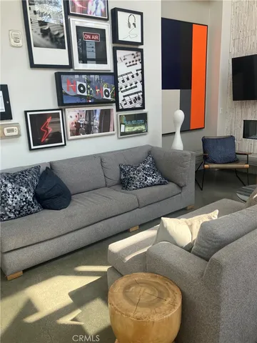 a living room with couches and kitchen view with wooden floor