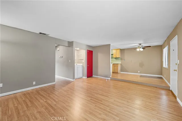 a view of an empty room with wooden floor and a bathroom
