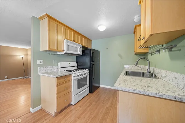 a kitchen with stainless steel appliances granite countertop a sink a stove and a wooden floors