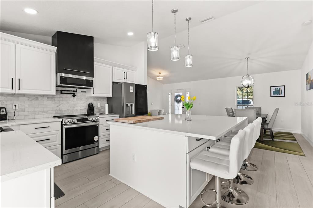 812 Chastain Road Seffner, FL 33584 - Photo 5 of 26 a large kitchen with kitchen island a stove a table a sink and a refrigerator