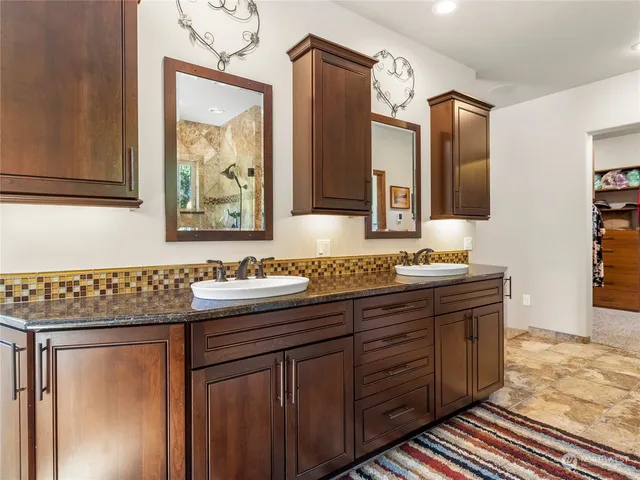 a bathroom with a granite countertop double vanity sink and mirror