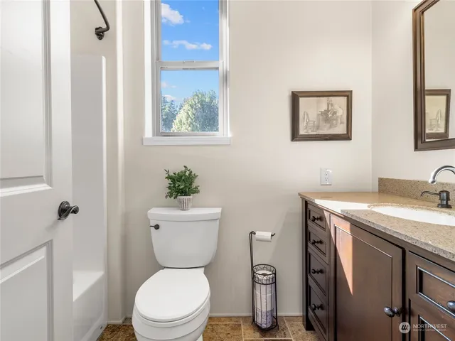 a bathroom with a granite countertop toilet a sink and a mirror